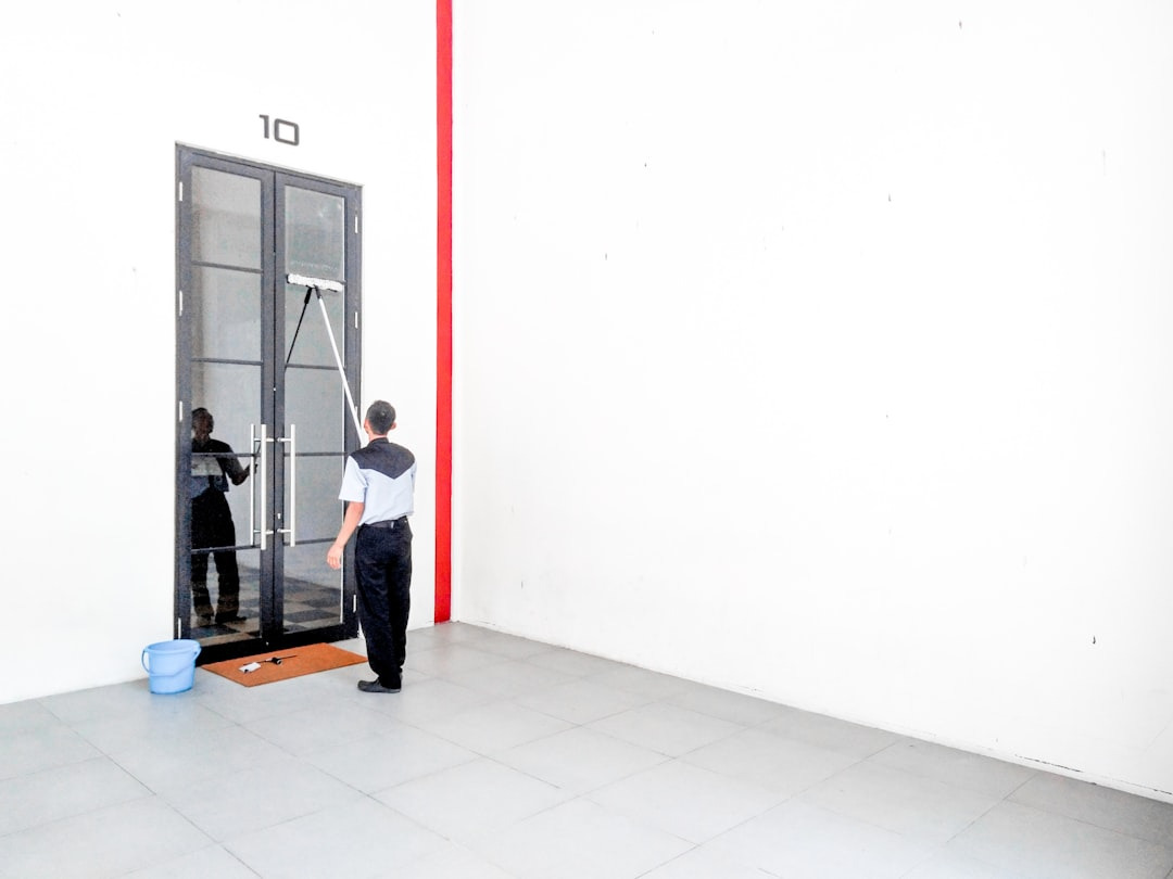 Maintenance worker cleaning glass doors with a squeegee.